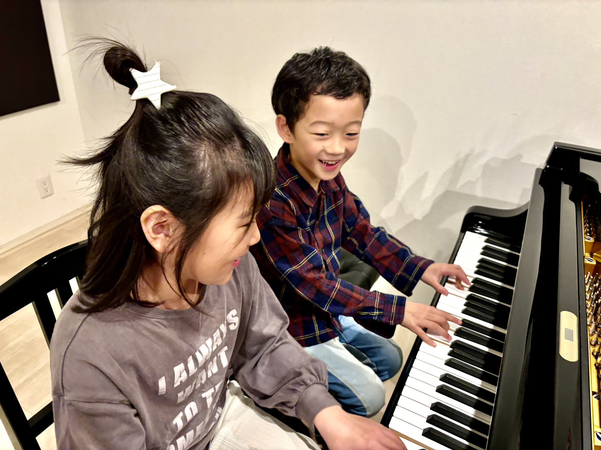 男の子と女の子が笑顔でピアノを弾く